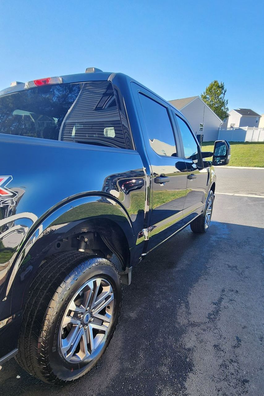 A black truck is parked in a parking lot on a sunny day.