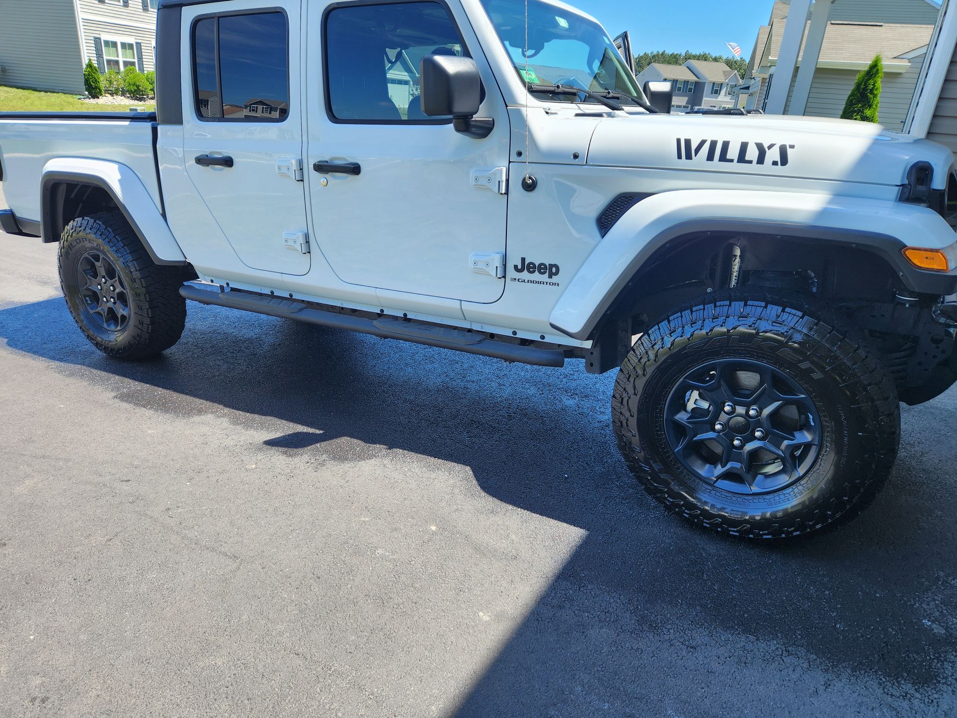A white jeep with the word willys on the side is parked in a driveway.