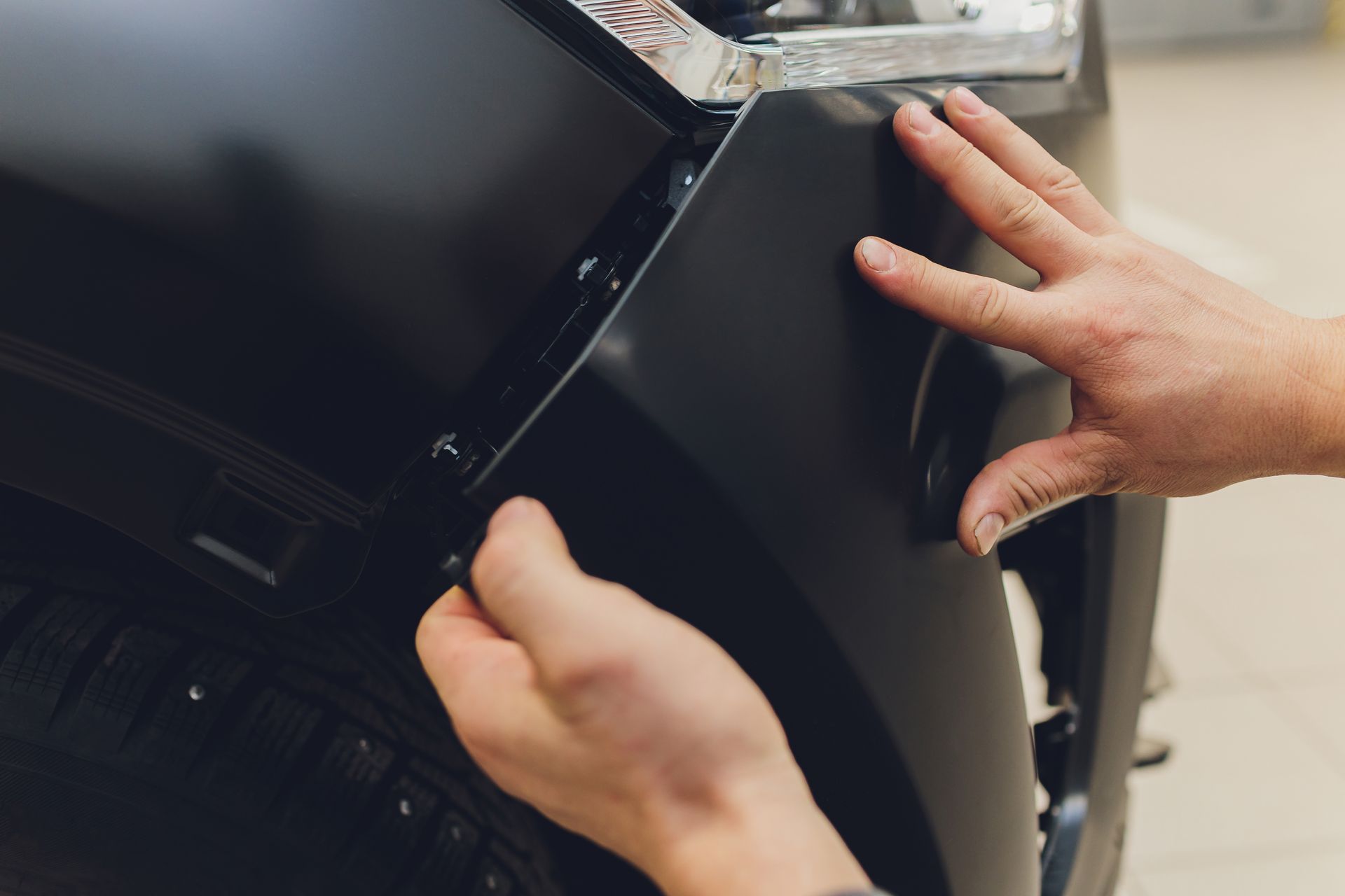 A person is holding a piece of plastic on the front of a car.