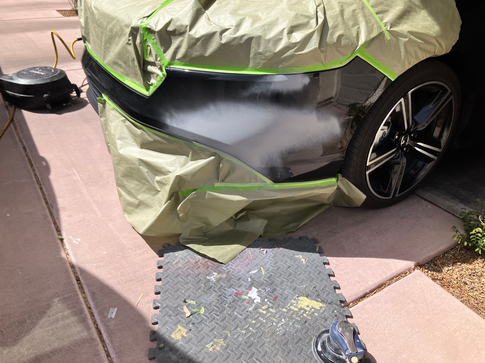 A car is covered in green tape and smoke is coming out of it.