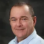 A man in a blue shirt is smiling for the camera.