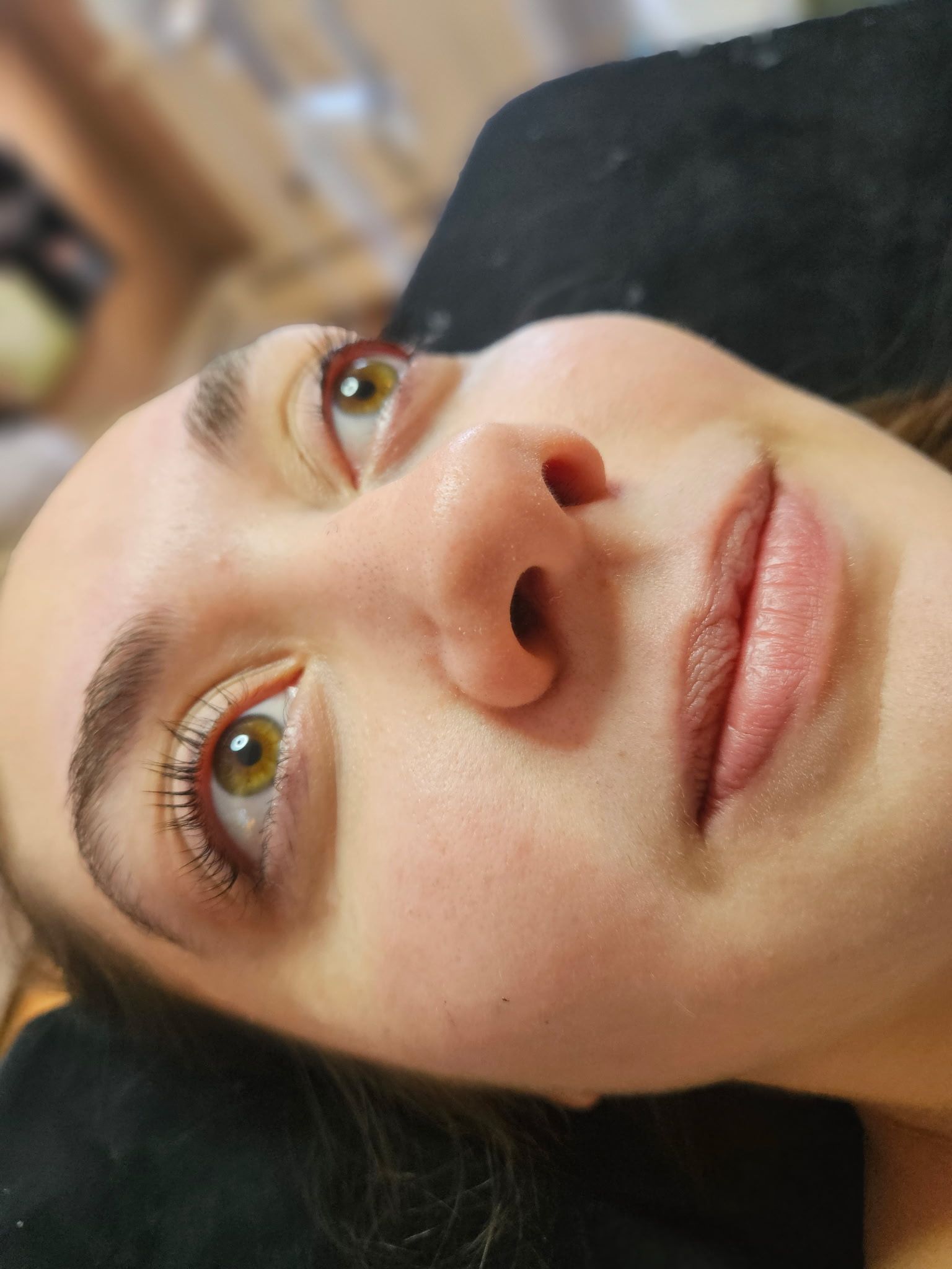 Close-up of a woman's face, angled upward, light skin, green eyes, subtle makeup, focused expression.