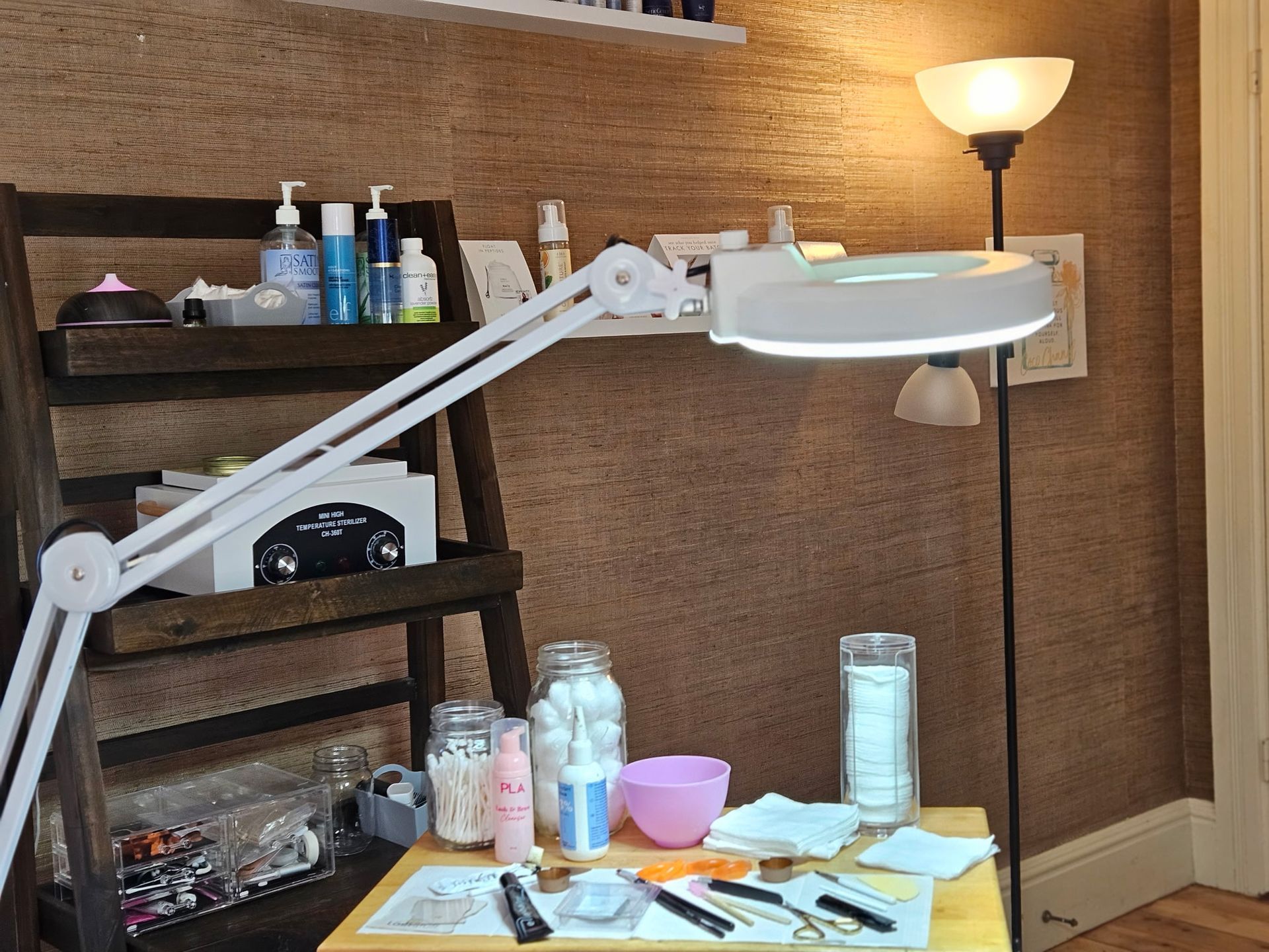 A work station with a magnifying lamp, brown cork wall, and supplies.
