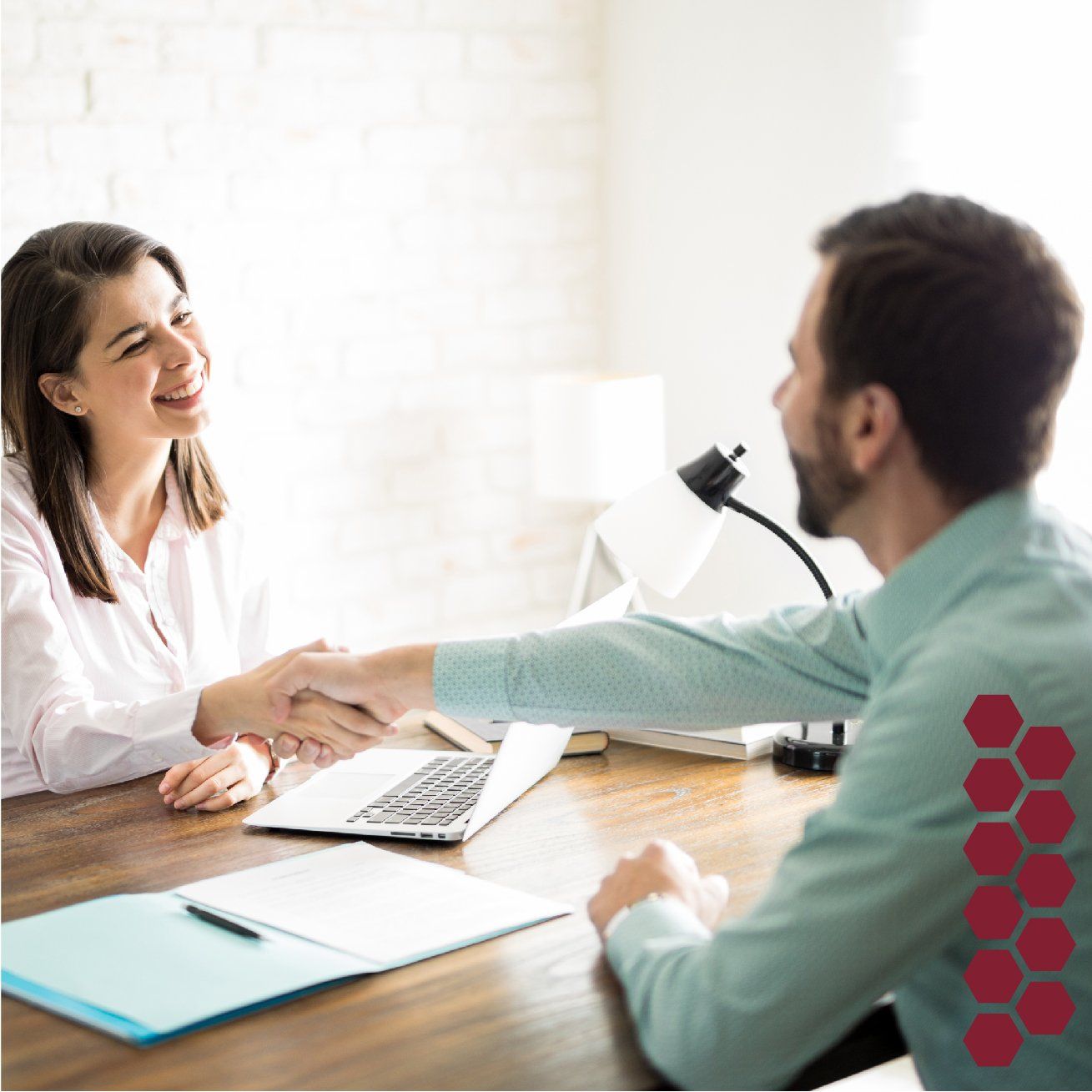 Un hombre y una mujer se dan la mano mientras están sentados en una mesa.