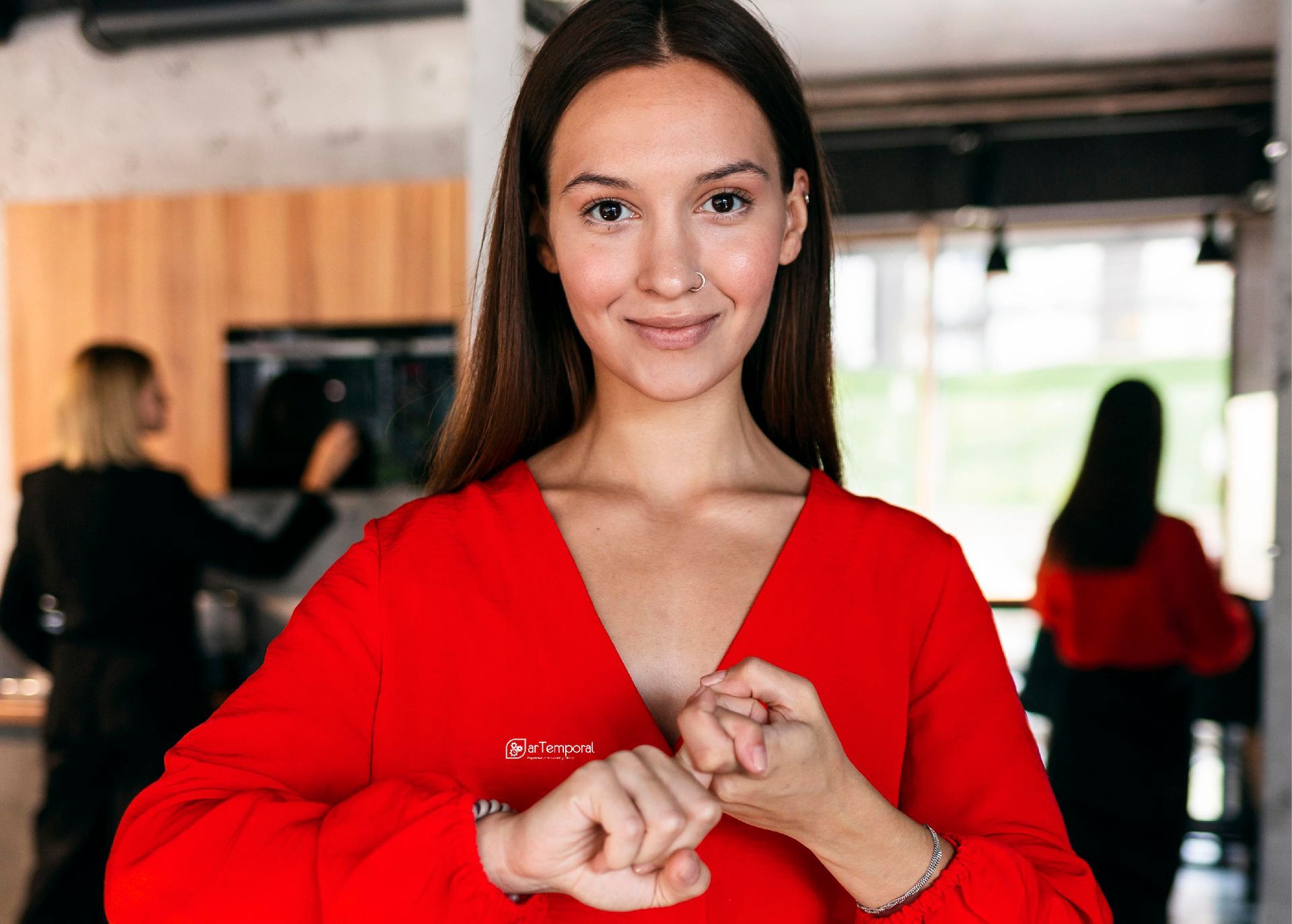 Una mujer con un suéter rojo mira su reloj.