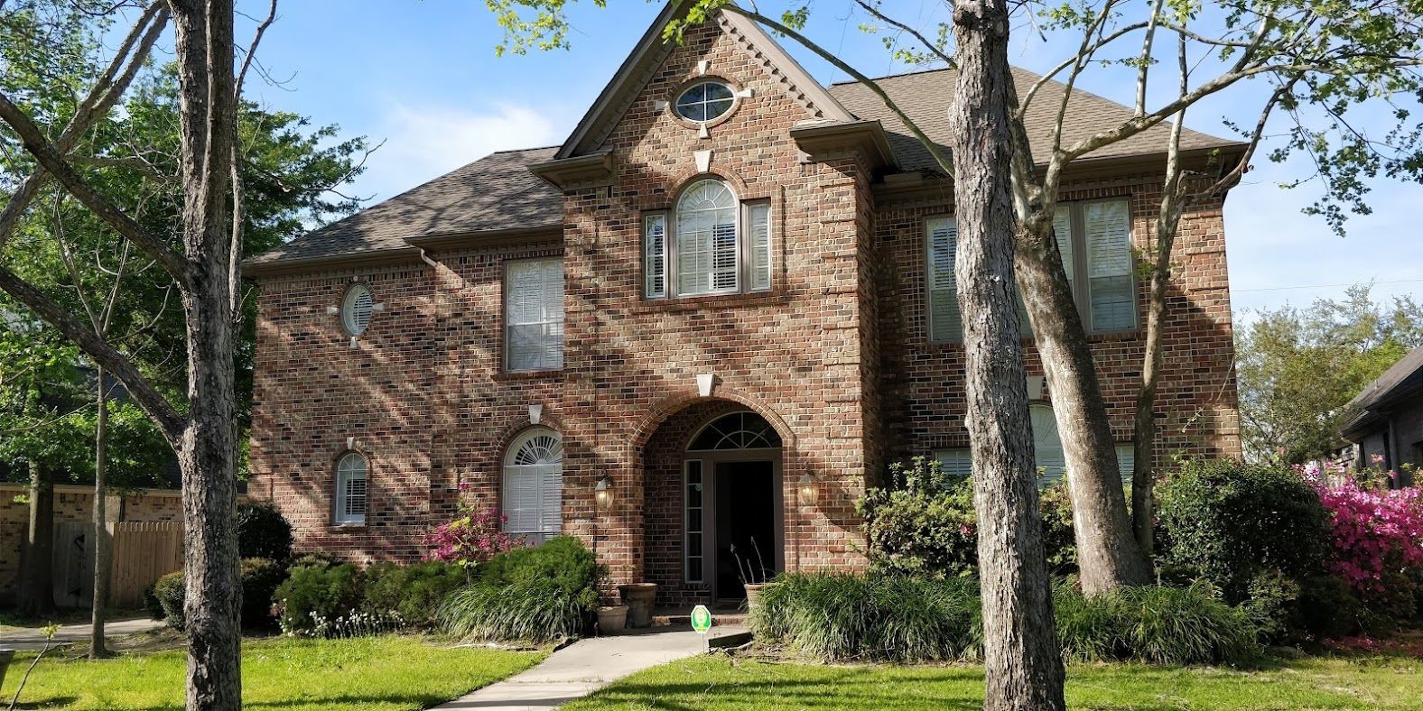 A large brick house with a lot of windows and trees in front of it.