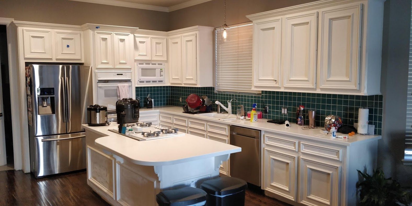A kitchen with white cabinets , stainless steel appliances , and a large island.