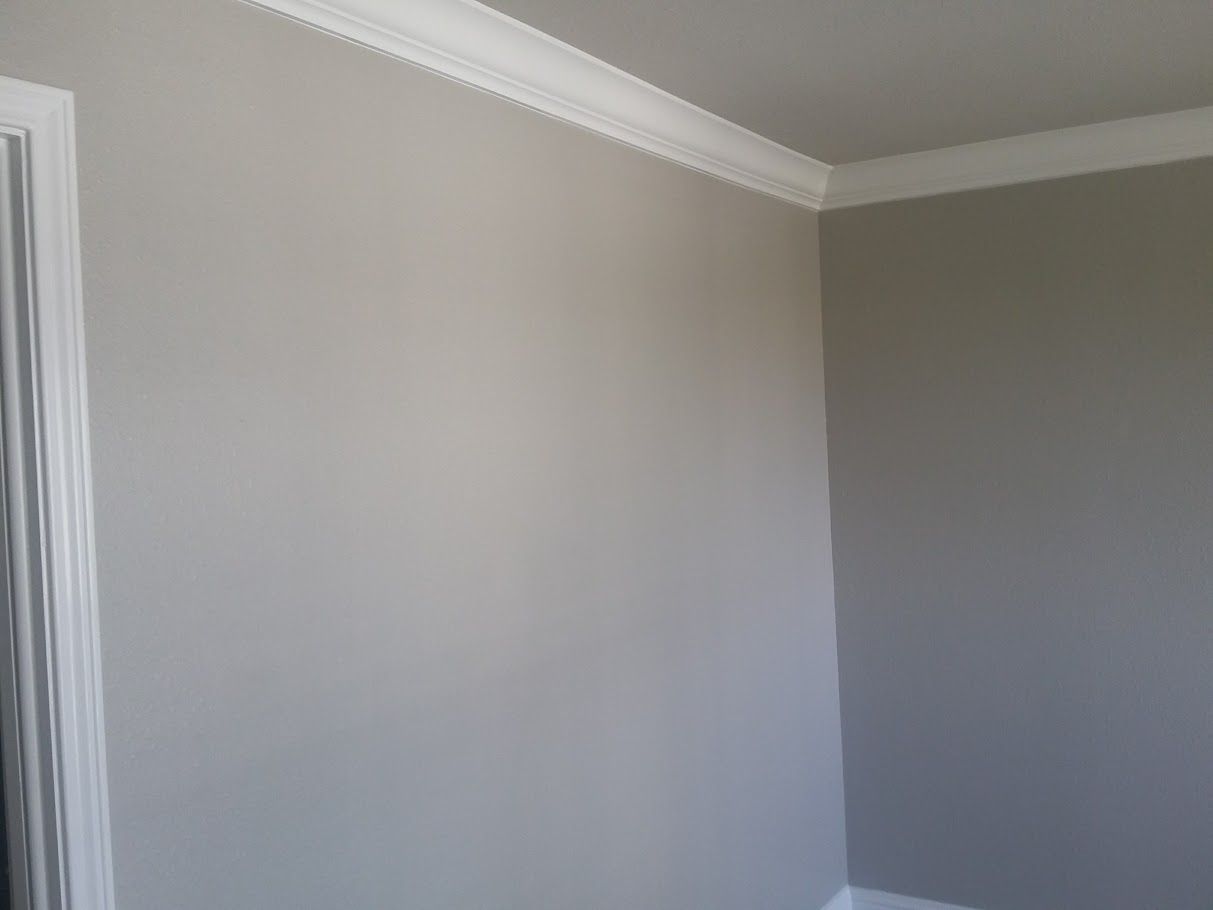 A room with gray walls and white trim and a door.