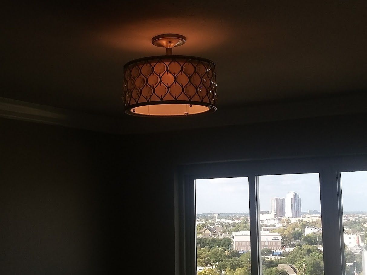 A lamp is hanging from the ceiling in front of a window.