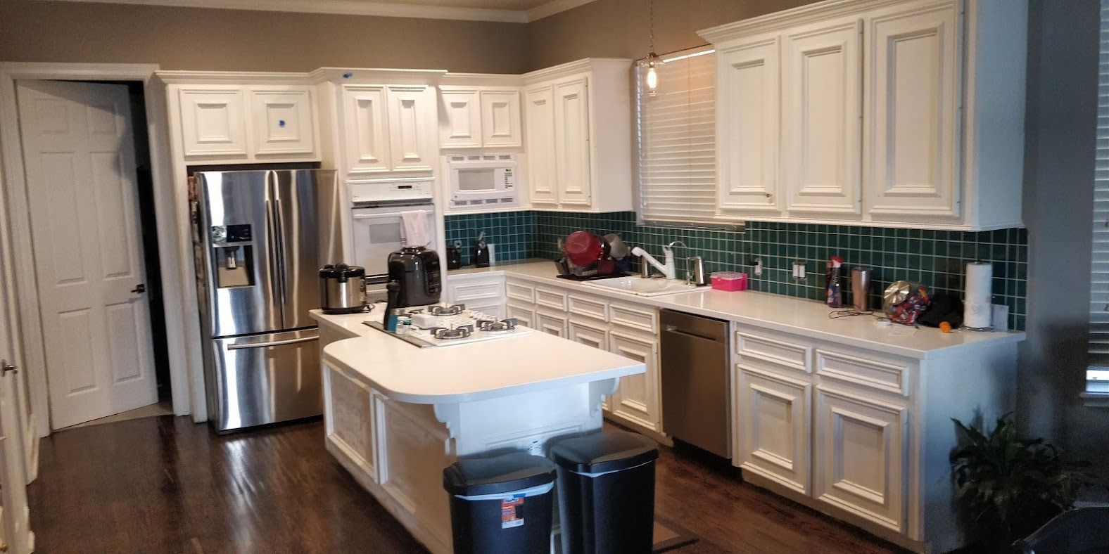 A kitchen with white cabinets , stainless steel appliances , and a large island.