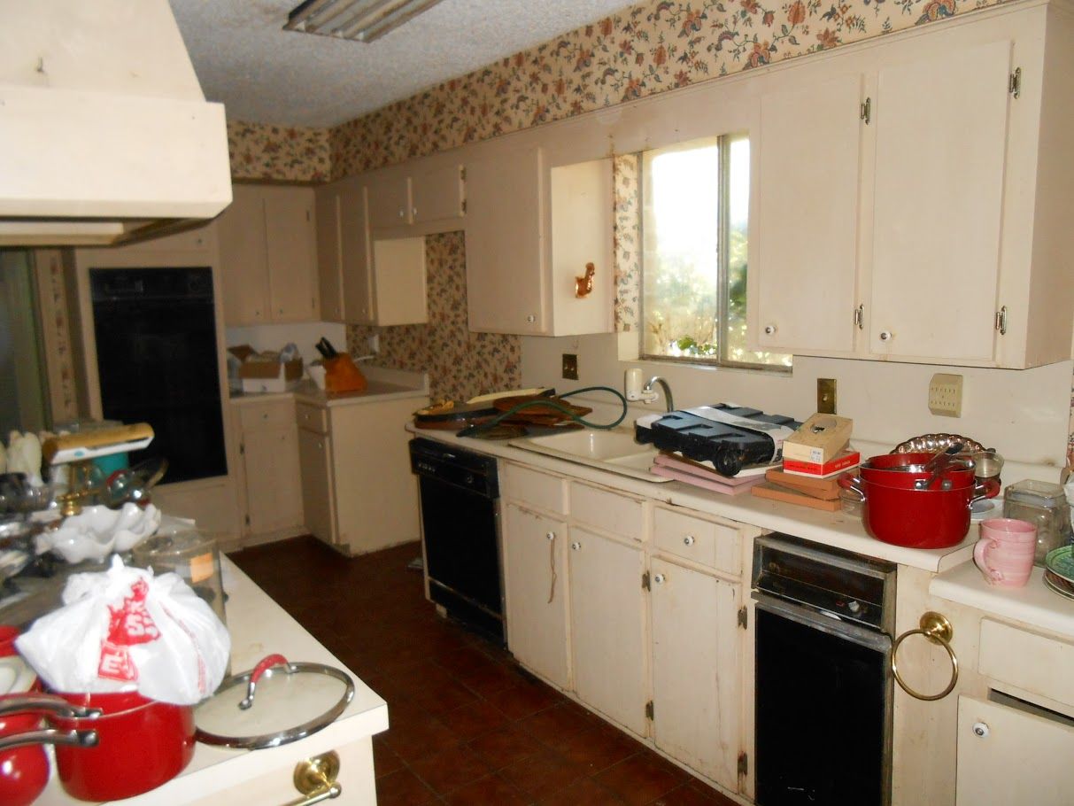 A kitchen with white cabinets and red pots and pans