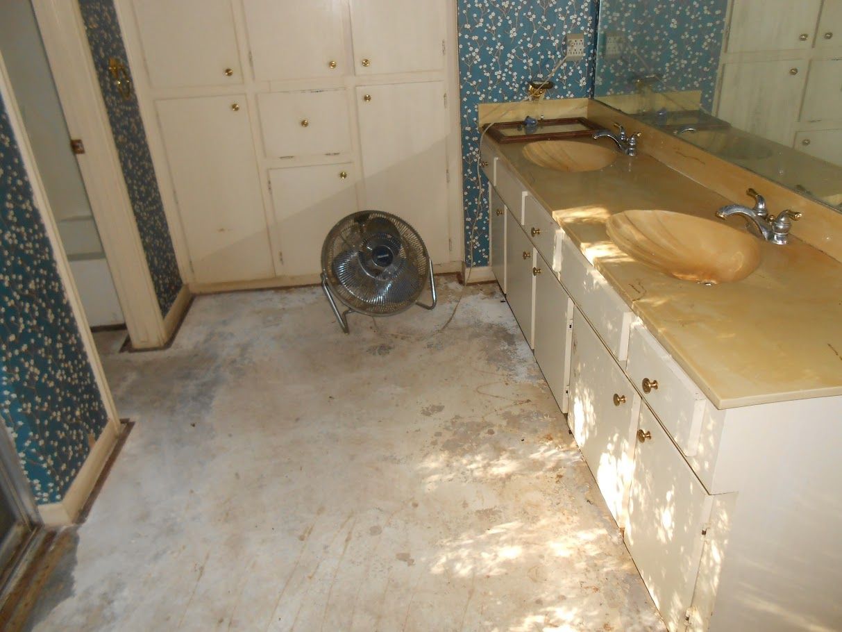 A bathroom with a sink and a fan on the floor