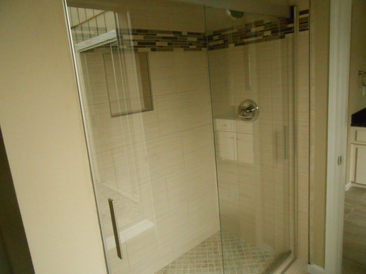 A bathroom with a walk in shower with a glass door