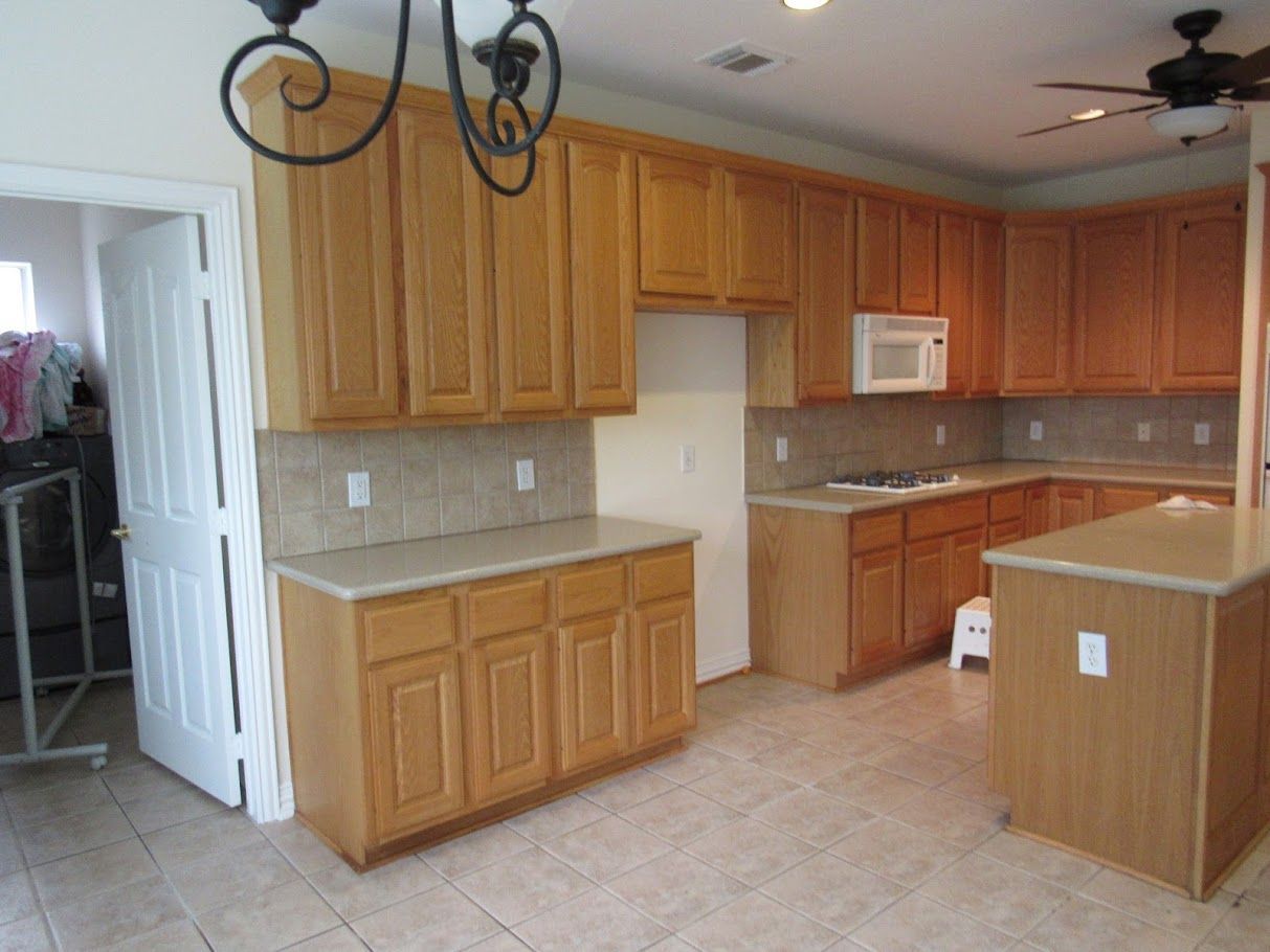 A kitchen with wooden cabinets and a ceiling fan