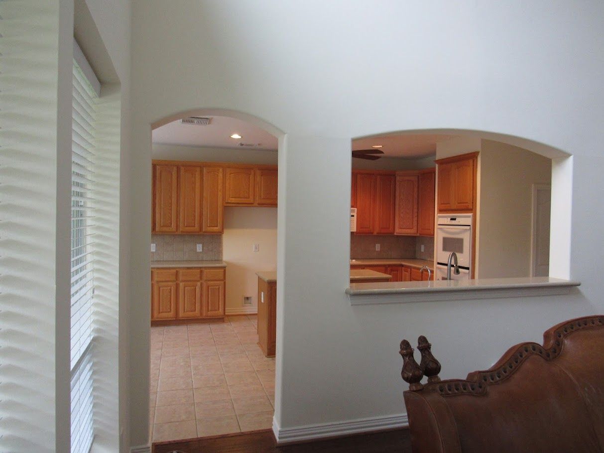 A living room looking into a kitchen with wooden cabinets