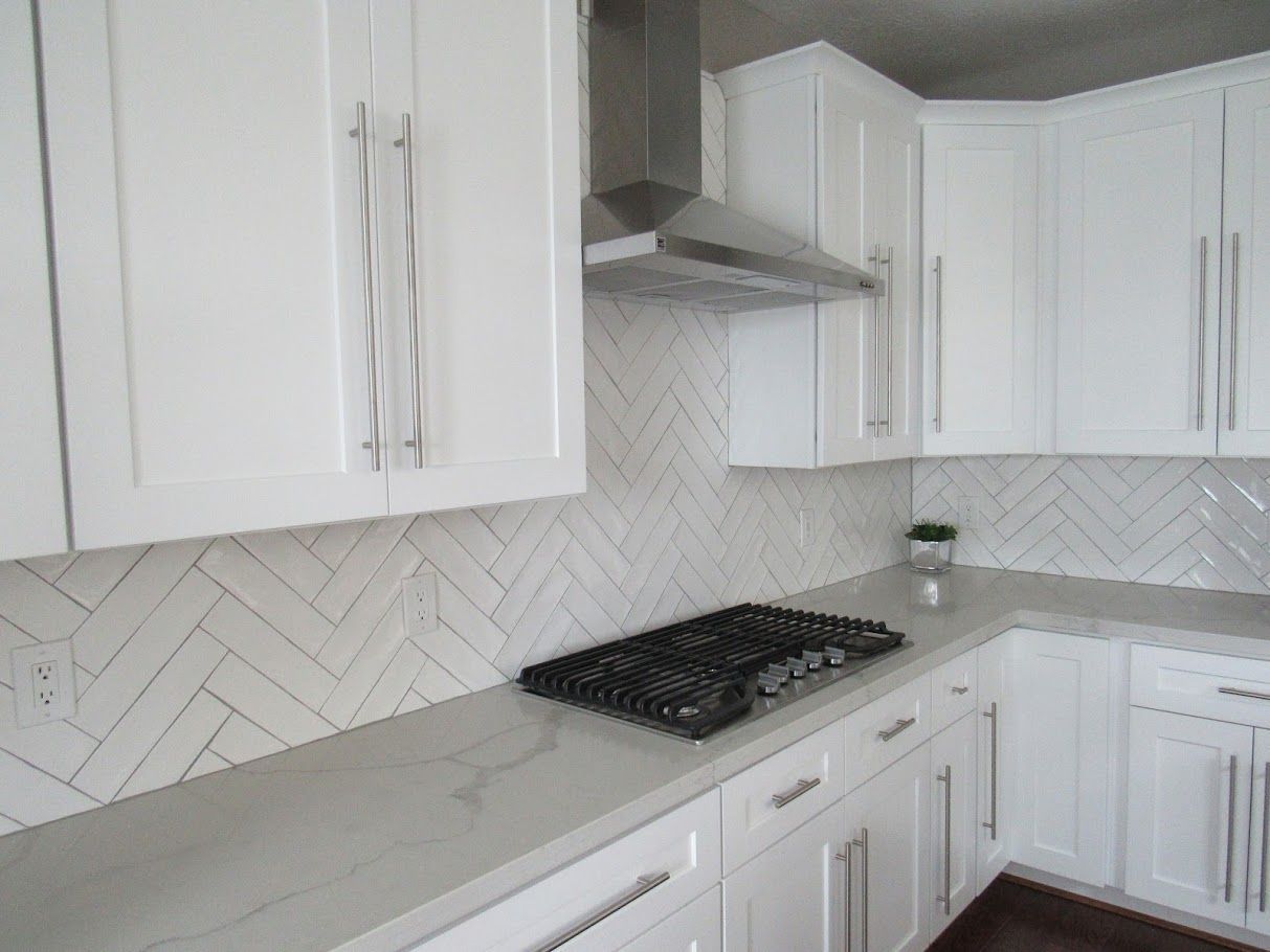 A kitchen with white cabinets and a stove top oven.