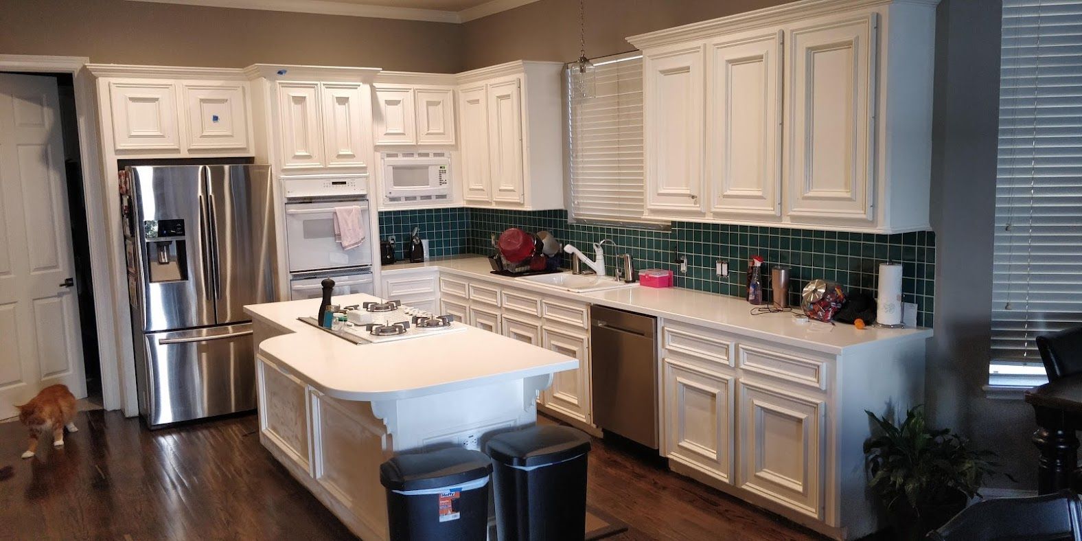 A kitchen with white cabinets , stainless steel appliances , and a large island.