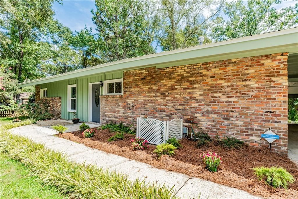 A brick house with a green roof and a walkway leading to it.