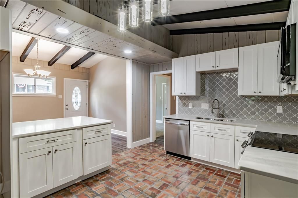 A kitchen with white cabinets and a brick floor.