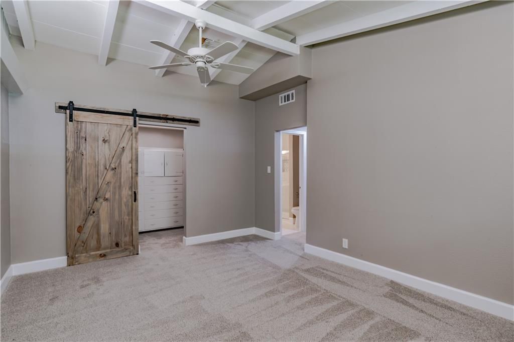 An empty room with a sliding barn door and a ceiling fan.