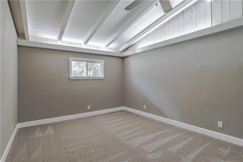 An empty room with a window and a ceiling fan.