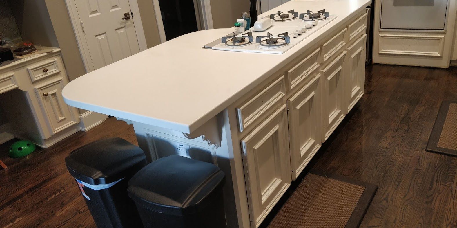 A kitchen with a large island and two trash cans.