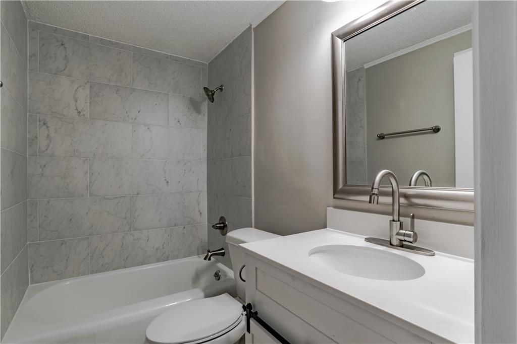 A bathroom with a toilet , sink , and mirror.