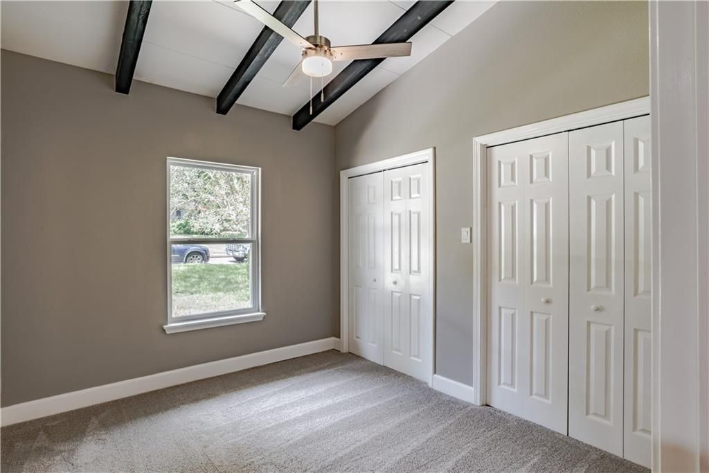 An empty bedroom with a ceiling fan and a window.
