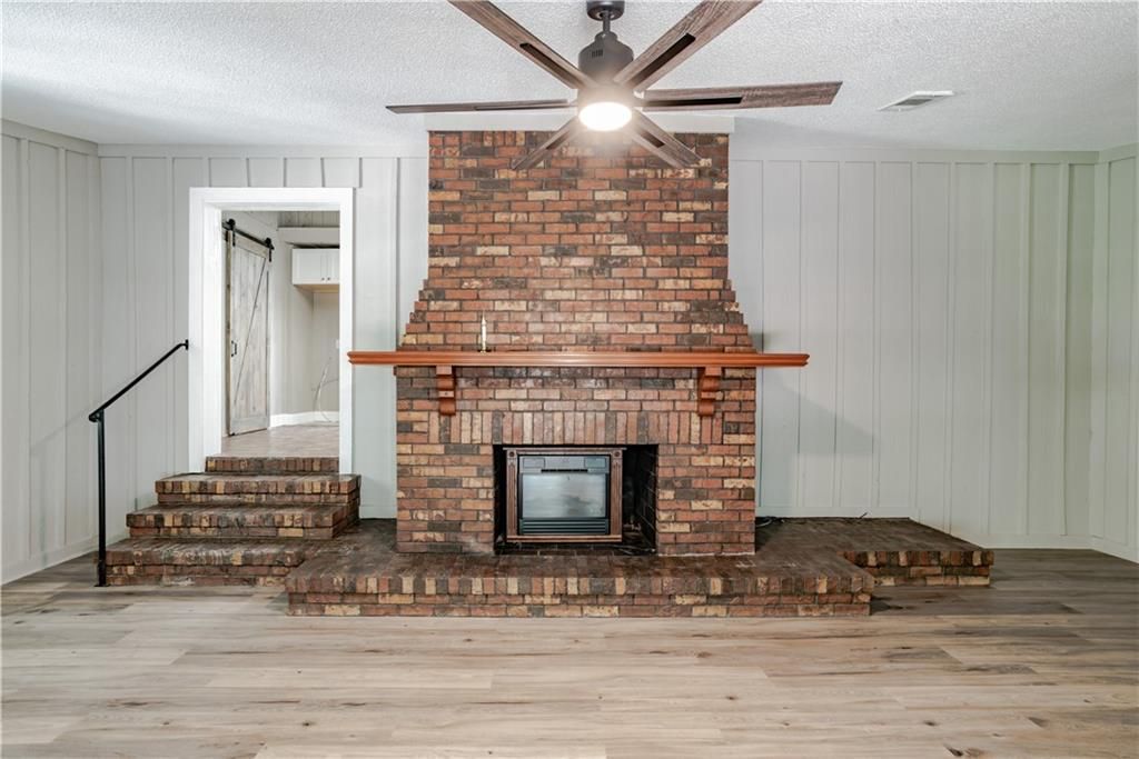 A living room with a brick fireplace and a ceiling fan.