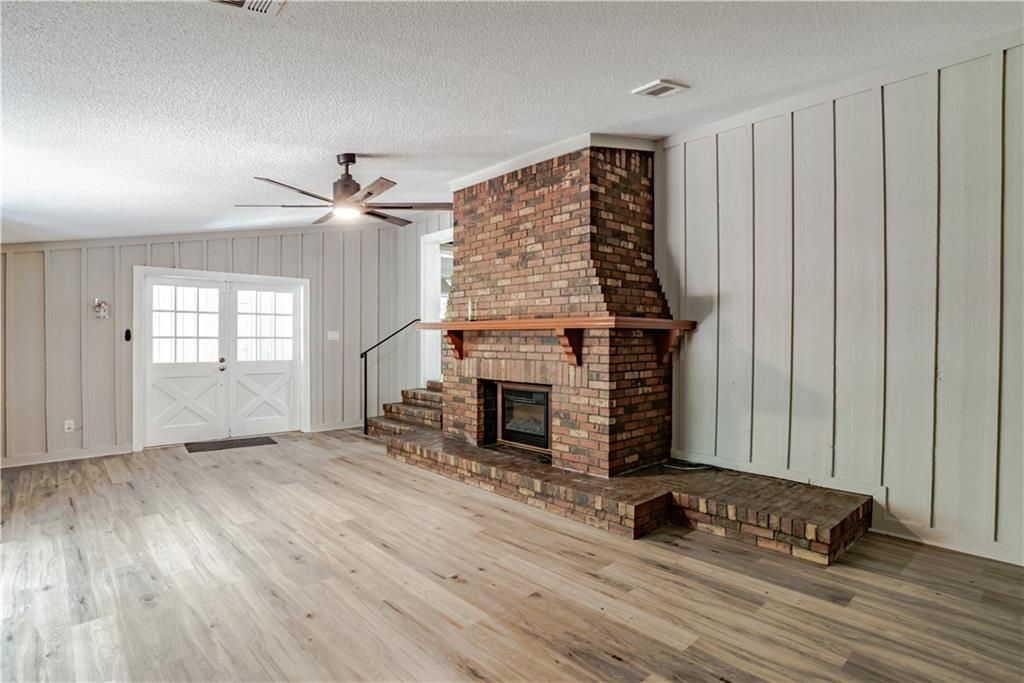 A living room with a brick fireplace and wooden floors.