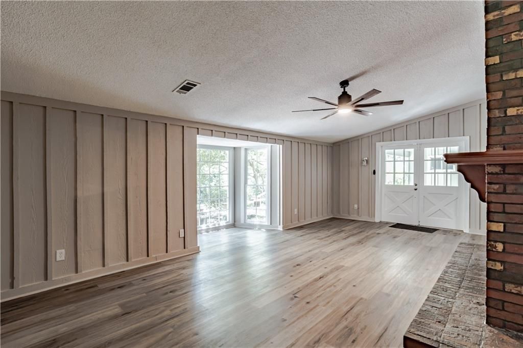 An empty living room with hardwood floors and a ceiling fan.