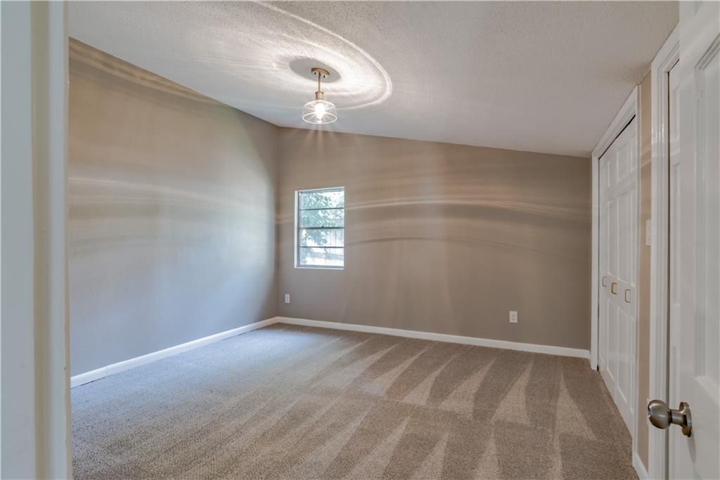 An empty bedroom with a ceiling fan and a window.