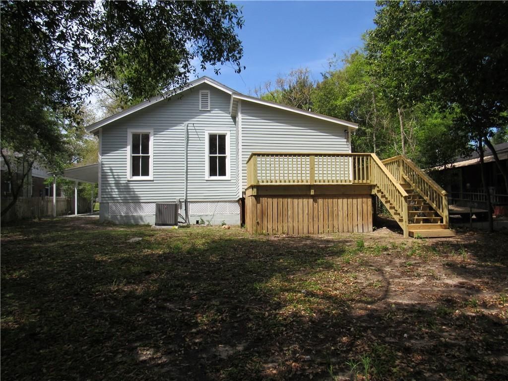 A white house with a wooden deck and stairs