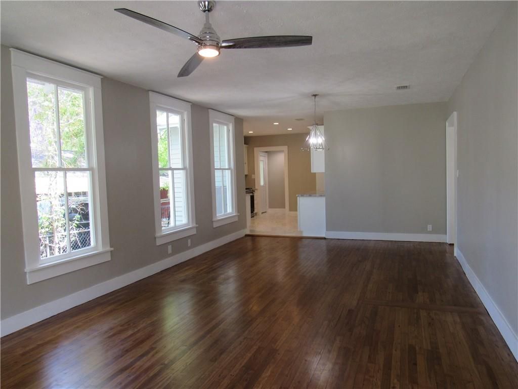 An empty living room with hardwood floors and a ceiling fan.