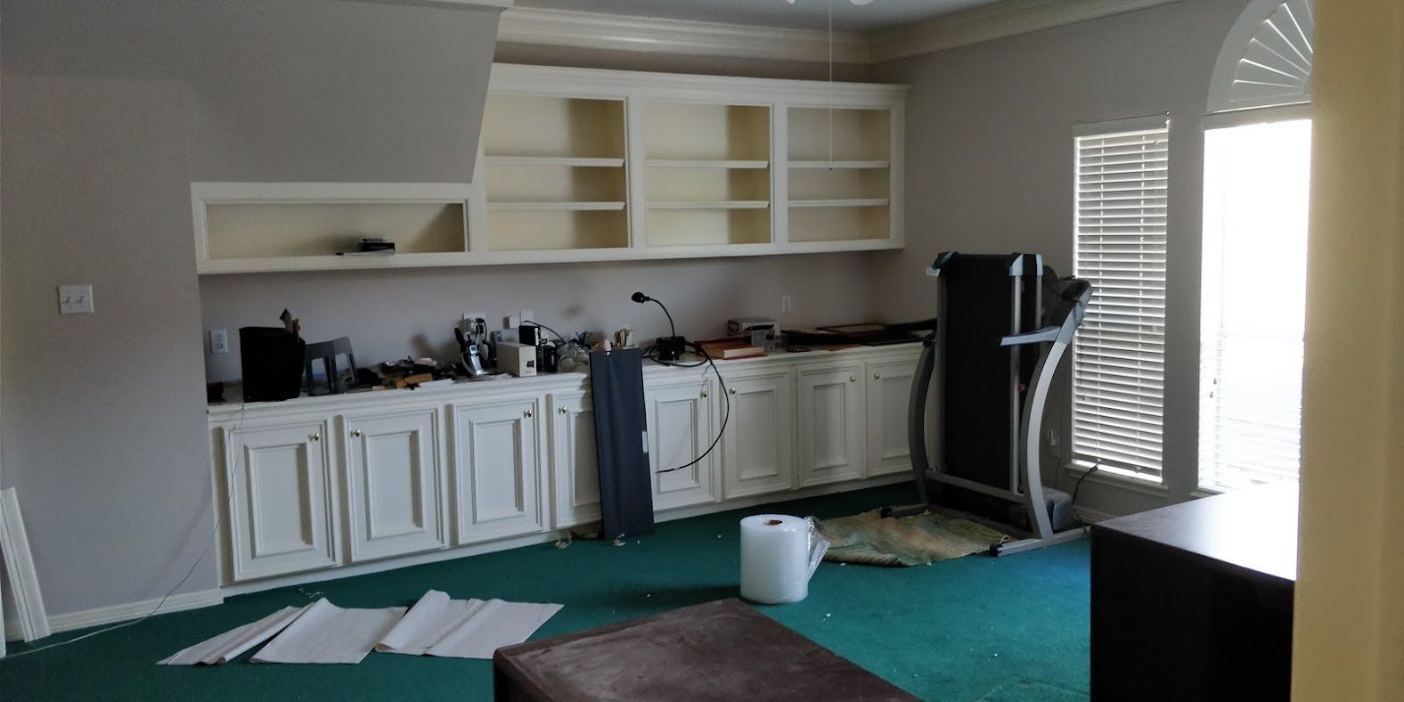 An empty room with a treadmill in it.