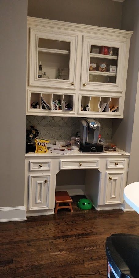 A kitchen with white cabinets and a coffee maker.