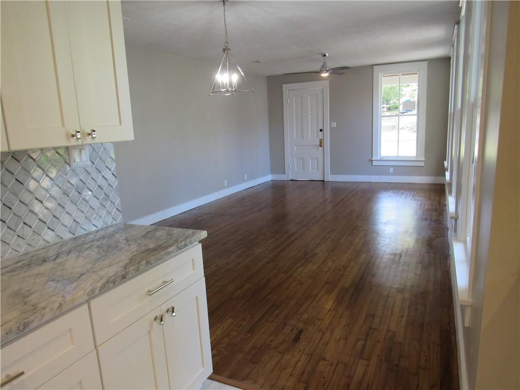 An empty living room with hardwood floors and white cabinets