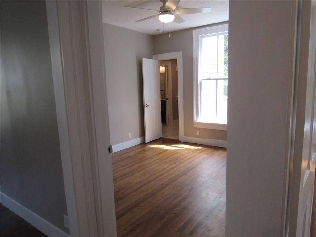 An empty room with hardwood floors and a ceiling fan