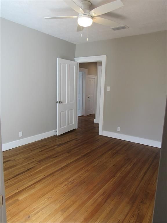 An empty room with hardwood floors and a ceiling fan
