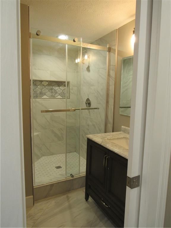 A bathroom with a walk in shower and a sink