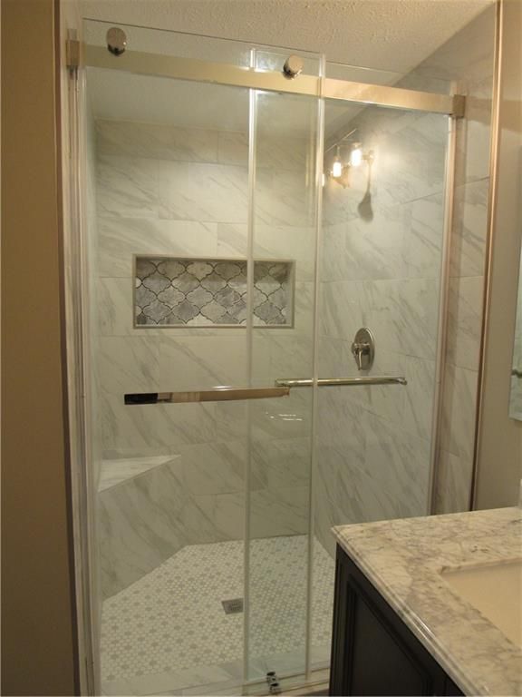 A bathroom with a sliding glass shower door and a sink.