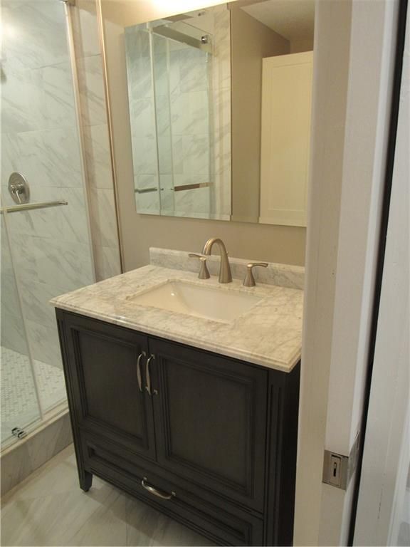 A bathroom with a sink , mirror and shower.