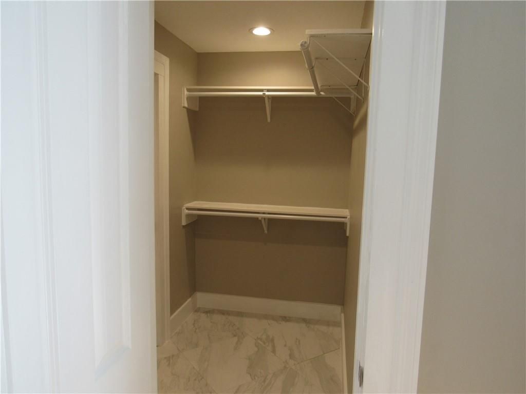 A walk in closet with shelves and a marble floor.