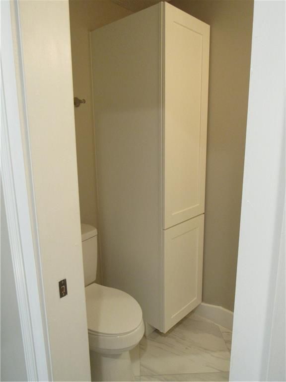 A bathroom with a toilet and a tall white cabinet