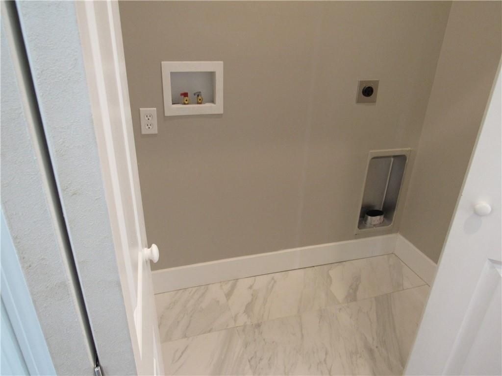 A laundry room with a marble floor and a white door.