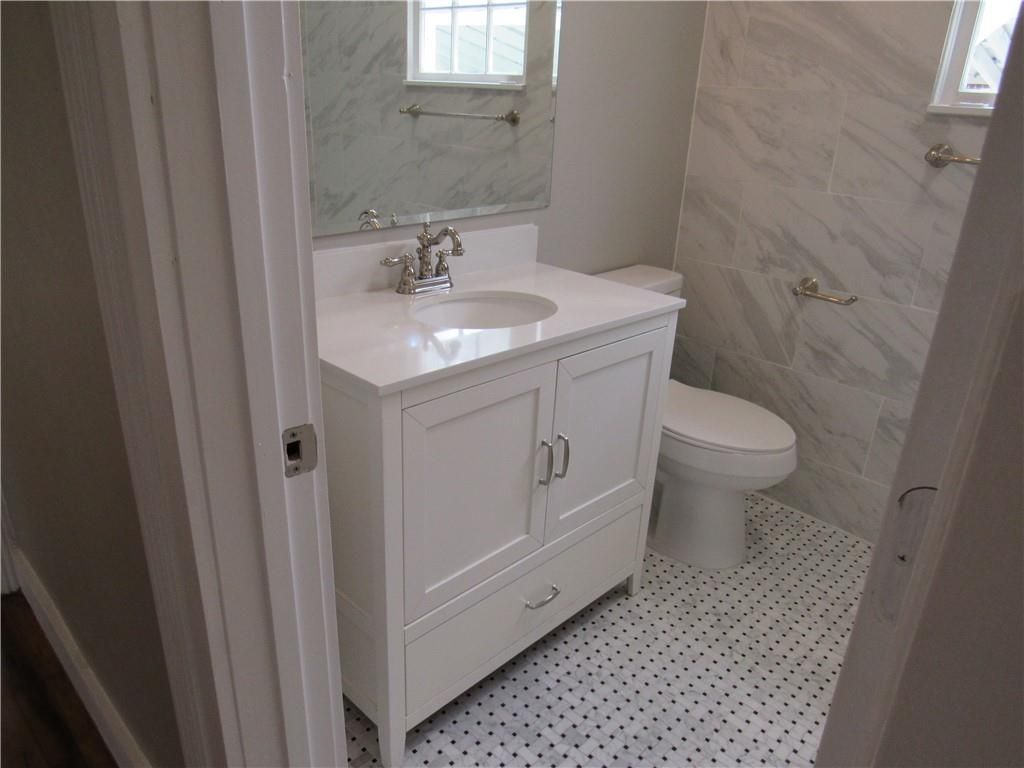 A bathroom with a sink, toilet and mirror.