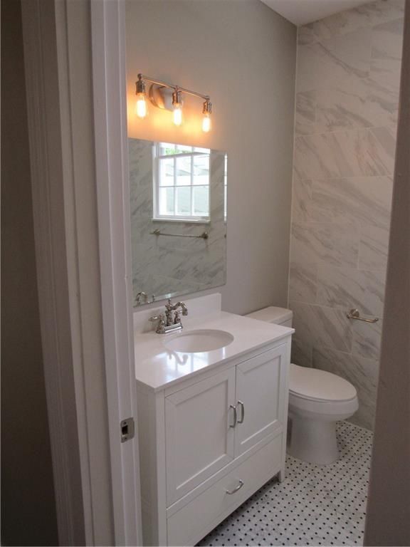 A bathroom with a sink a toilet and a mirror