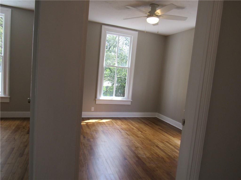 An empty room with hardwood floors and a ceiling fan