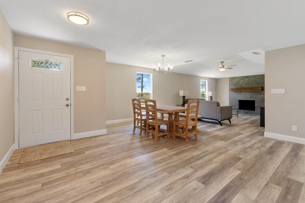 A living room with hardwood floors, a table and chairs, and a fireplace.