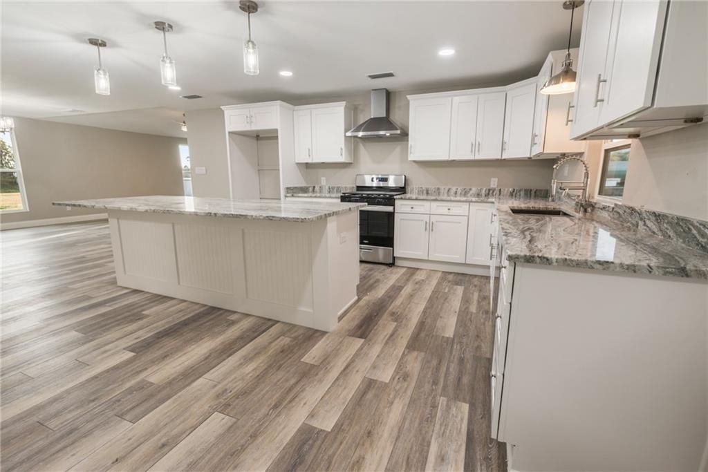 A kitchen with white cabinets , granite counter tops , and a large island.